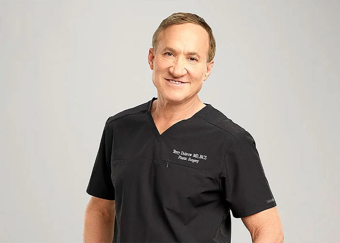 Doctor in black scrubs smiling, expert on male celebrities looking unrecognizable